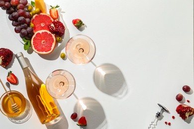 Photo of Flat lay composition with tasty rose wine and snacks on white table. Space for text