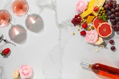 Flat lay composition with tasty rose wine and snacks on white marble table. Space for text