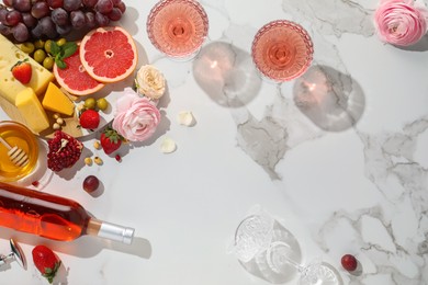 Flat lay composition with tasty rose wine and snacks on white marble table. Space for text