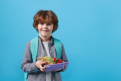 Cute little boy with lunch box on light blue background. Space for text