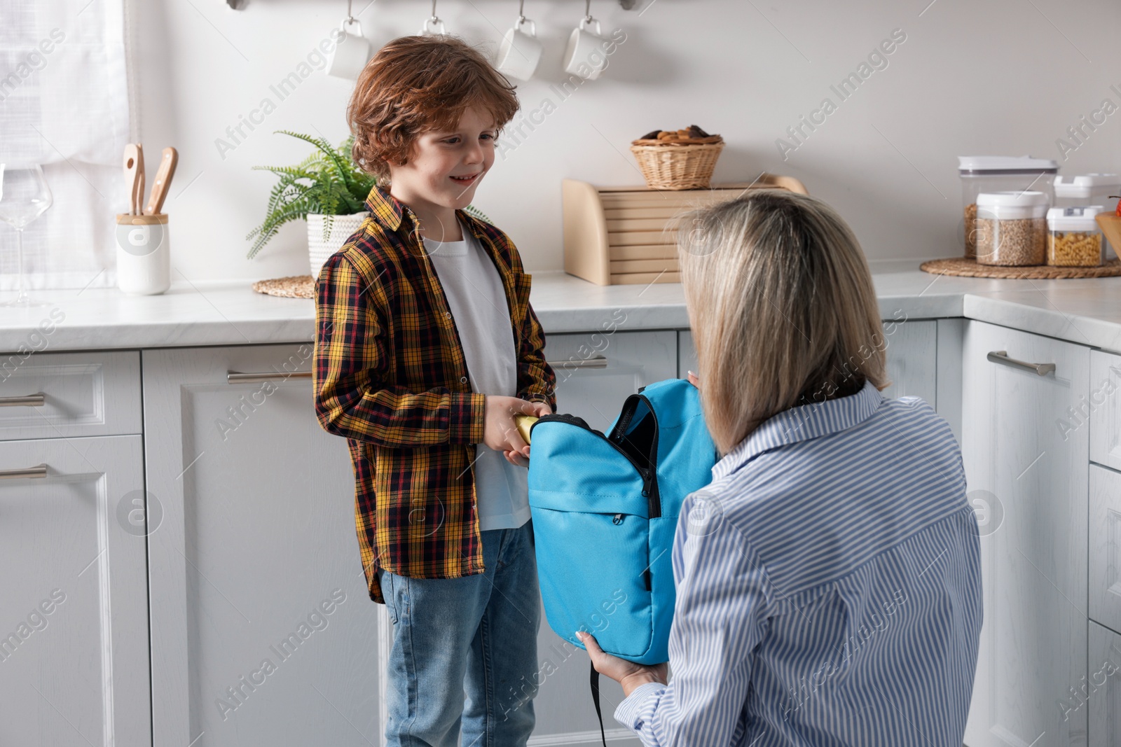 Photo of Mother packing her son's lunch in kitchen