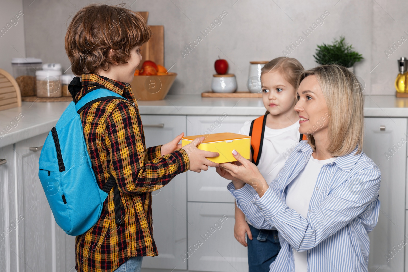 Photo of Mother giving her children lunch in kitchen