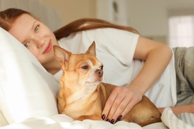 Photo of Teenage girl with her cute Chihuahua dog on bed at home, selective focus