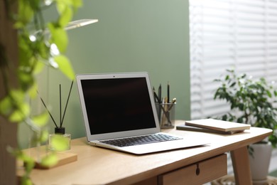 Photo of Home office. Comfortable workplace with laptop and stationery on wooden desk in room