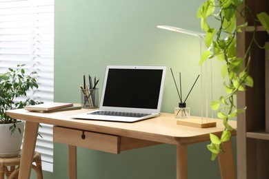 Photo of Home office. Comfortable workplace with laptop and stationery on wooden desk in room