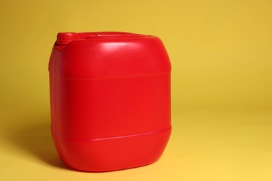 One red plastic canister on yellow background, space for text