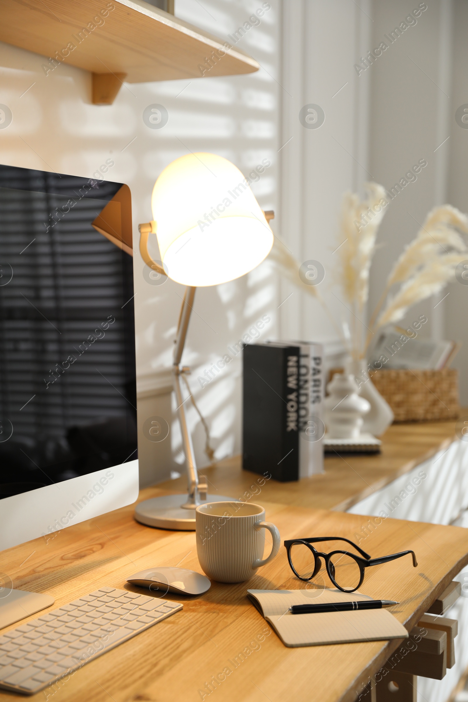 Photo of Comfortable workplace with computer, drink and glasses in home office, closeup