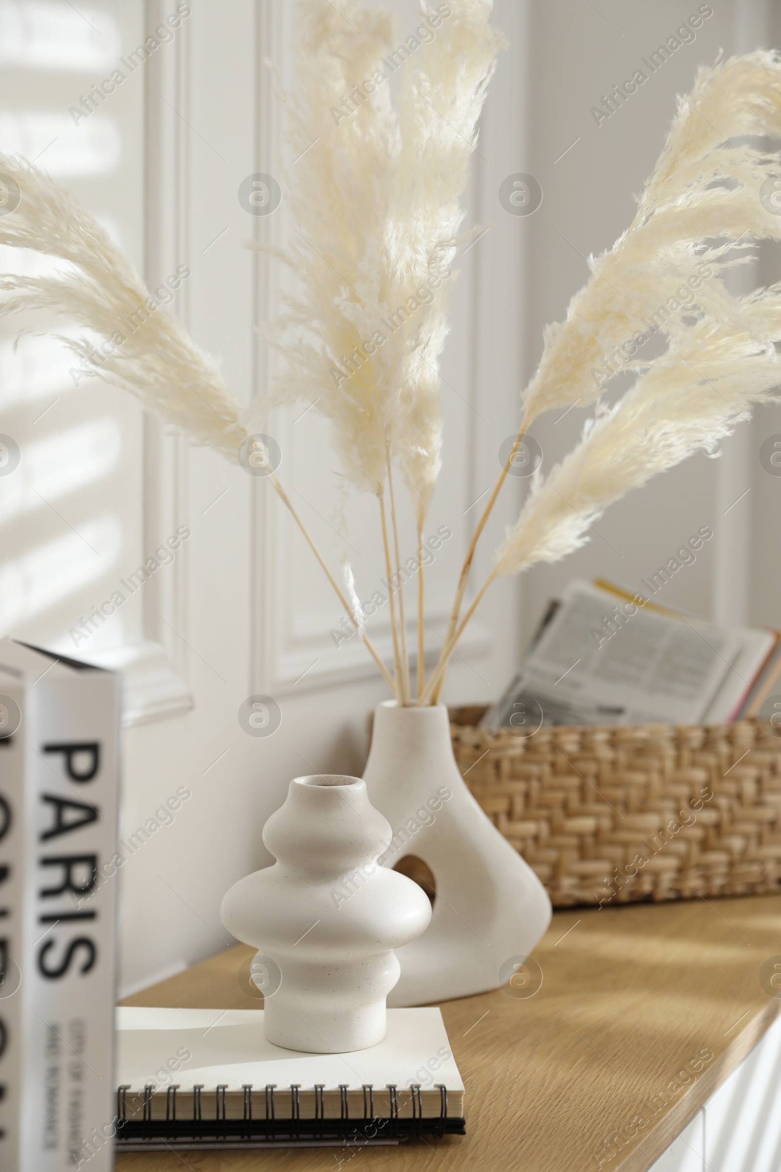 Photo of Vases with feathers and decor on wooden shelving unit indoors, closeup