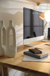 Photo of Comfortable workplace with computer and notebooks in home office, closeup