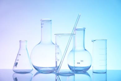 Photo of Laboratory glassware on mirror surface against color background