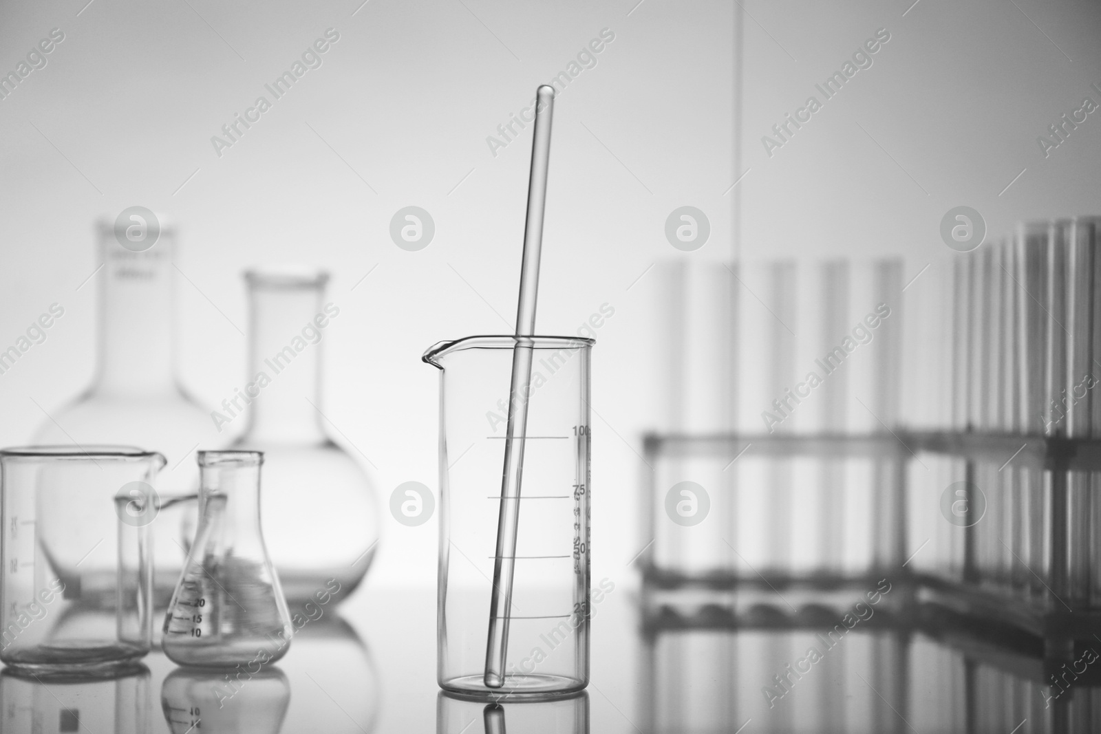 Photo of Laboratory glassware on mirror surface against light background