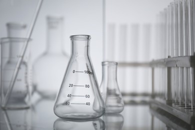 Photo of Laboratory glassware on mirror surface against light background