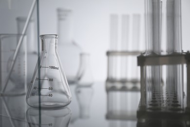 Laboratory glassware on mirror surface against light background