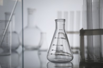 Laboratory glassware on mirror surface against light background