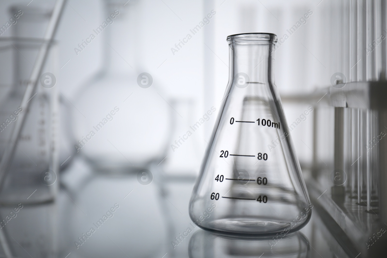 Photo of Laboratory glassware on mirror surface against light background