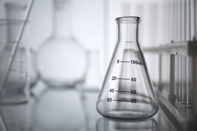 Laboratory glassware on mirror surface against light background