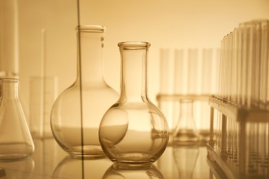 Photo of Laboratory glassware on mirror surface against color background