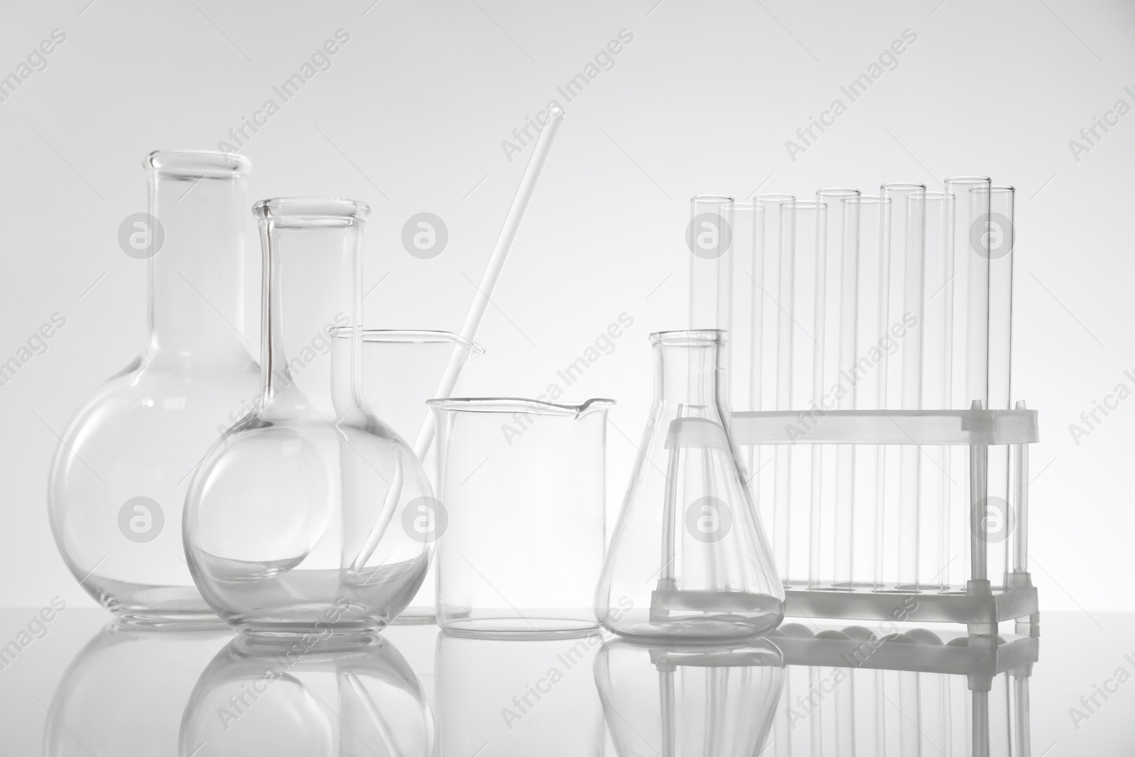 Photo of Laboratory glassware on mirror surface against light background