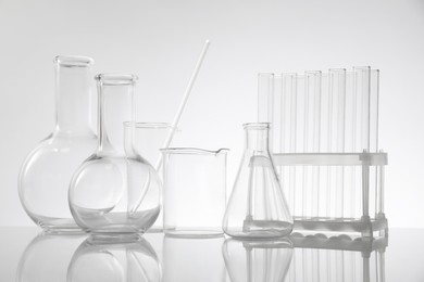 Photo of Laboratory glassware on mirror surface against light background