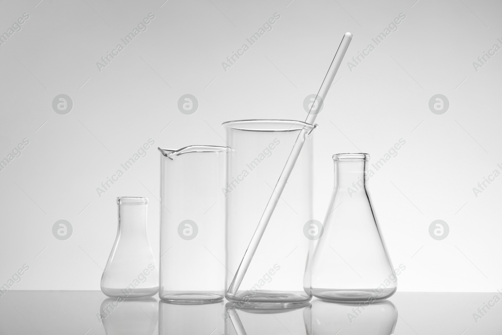 Photo of Laboratory glassware on mirror surface against light background