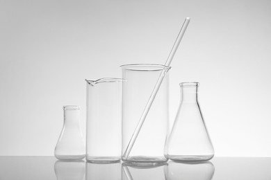 Photo of Laboratory glassware on mirror surface against light background