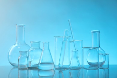 Laboratory glassware on mirror surface against light blue background