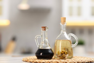 Photo of Bottles of salad dressings and olives on white table in kitchen, space for text