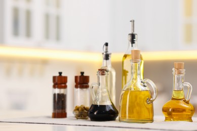 Photo of Bottles of salad dressings, salt, pepper and olives on white table in kitchen