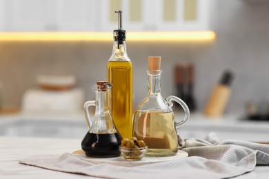 Photo of Bottles of salad dressings and olives on white table in kitchen