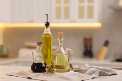 Photo of Bottles of salad dressings and olives on white table in kitchen