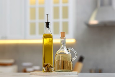 Photo of Bottles of salad dressings and olives on white table in kitchen