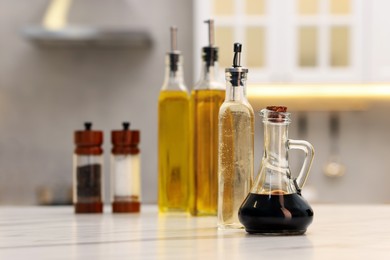 Photo of Bottles of salad dressings, salt and pepper on white table in kitchen