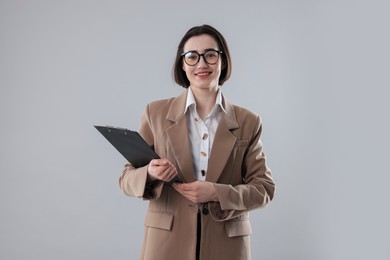 Portrait of young secretary with clipboard on grey background