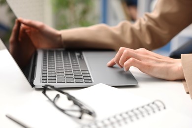 Photo of Secretary working on laptop at table in office, closeup