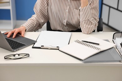 Photo of Secretary working on laptop at table in office, closeup