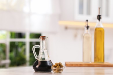 Photo of Salad dressings and olives on table in kitchen