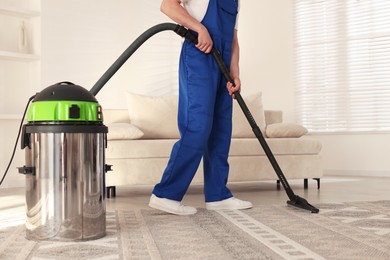 Photo of Cleaning service worker vacuuming rug with professional hoover at home, closeup