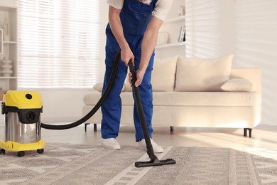 Photo of Cleaning service worker vacuuming rug with professional hoover at home, closeup