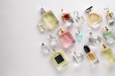 Photo of Bottles of various perfumes on light background, flat lay. Space for text