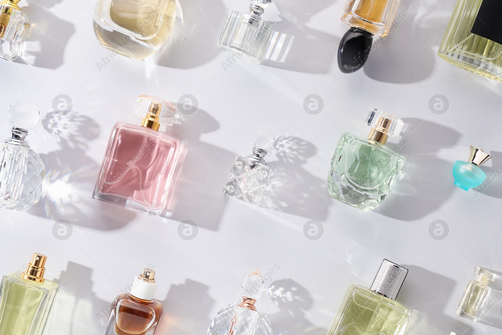 Bottles of various perfumes on light background, flat lay Photo of Bottles of various perfumes on light background, flat lay