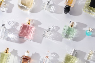 Photo of Bottles of various perfumes on light background, flat lay