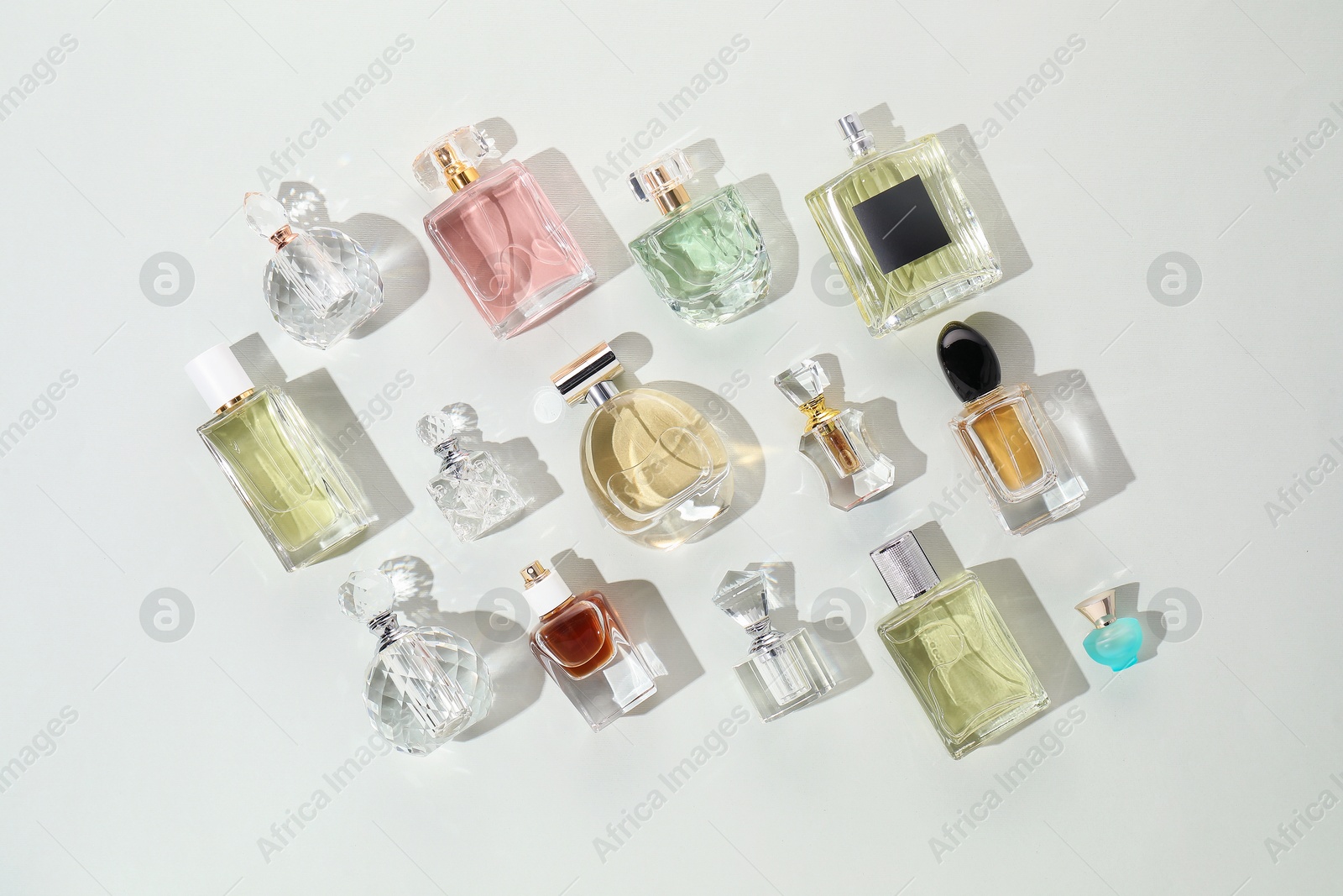 Bottles of various perfumes on light background, flat lay Photo of Bottles of various perfumes on light background, flat lay