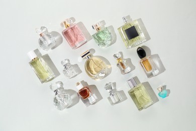 Photo of Bottles of various perfumes on light background, flat lay