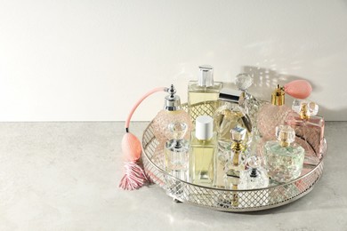 Photo of Different luxury perfumes and accessories on light textured table, space for text