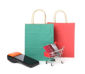 Photo of Payment terminal, shopping bags and mini cart with credit cards isolated on white