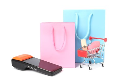 Photo of Payment terminal, shopping bags and mini cart with beauty products isolated on white