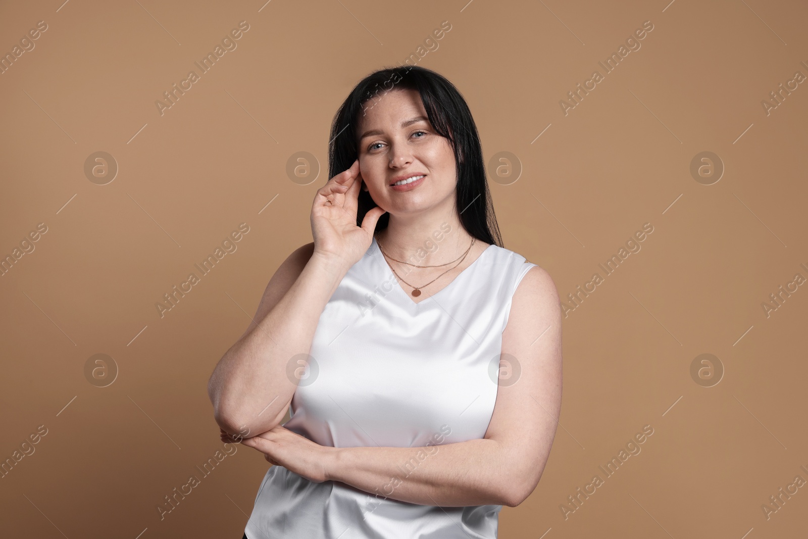 Photo of Portrait of smiling plus size model on beige background. Overweight