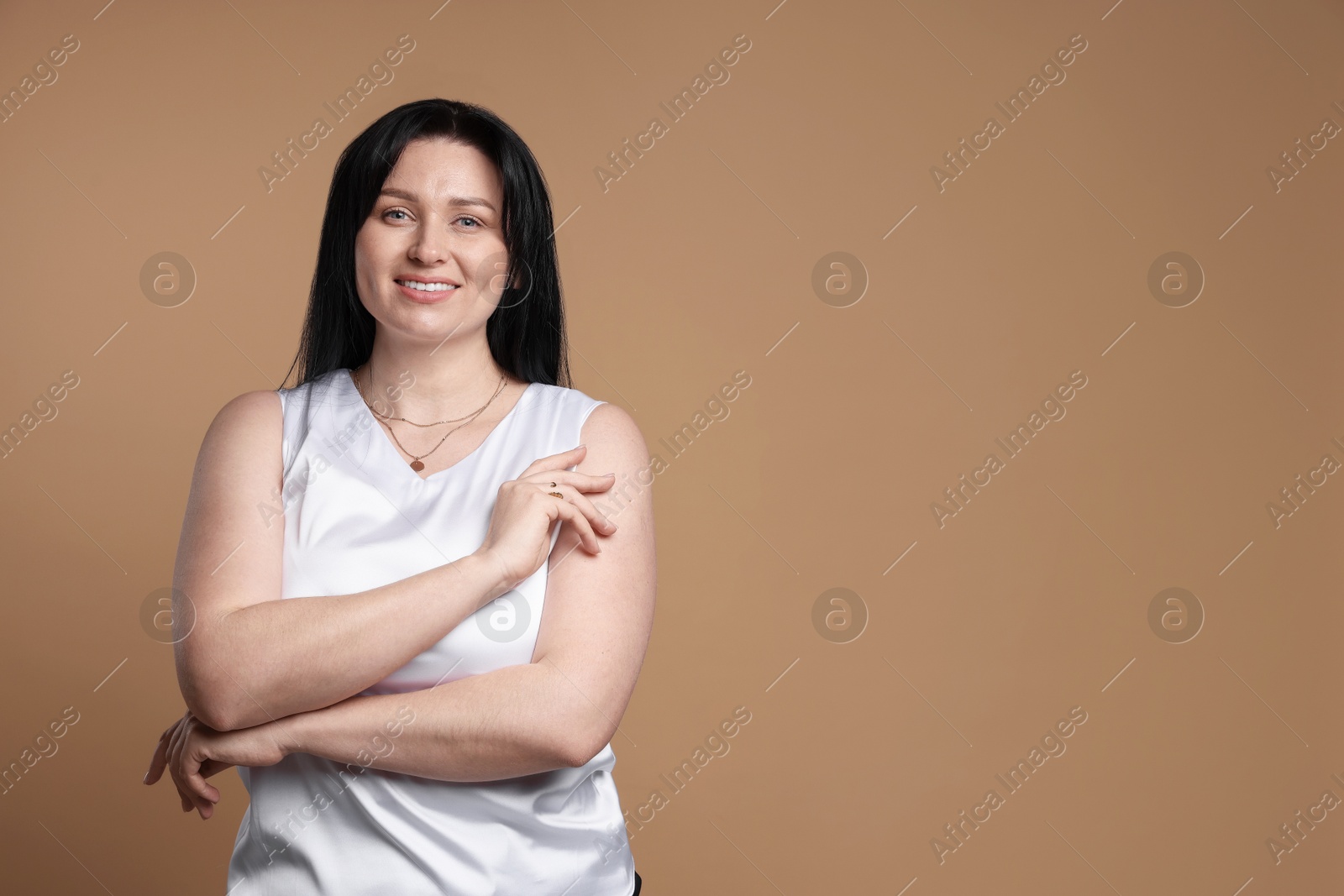 Photo of Portrait of smiling plus size model on beige background, space for text. Overweight