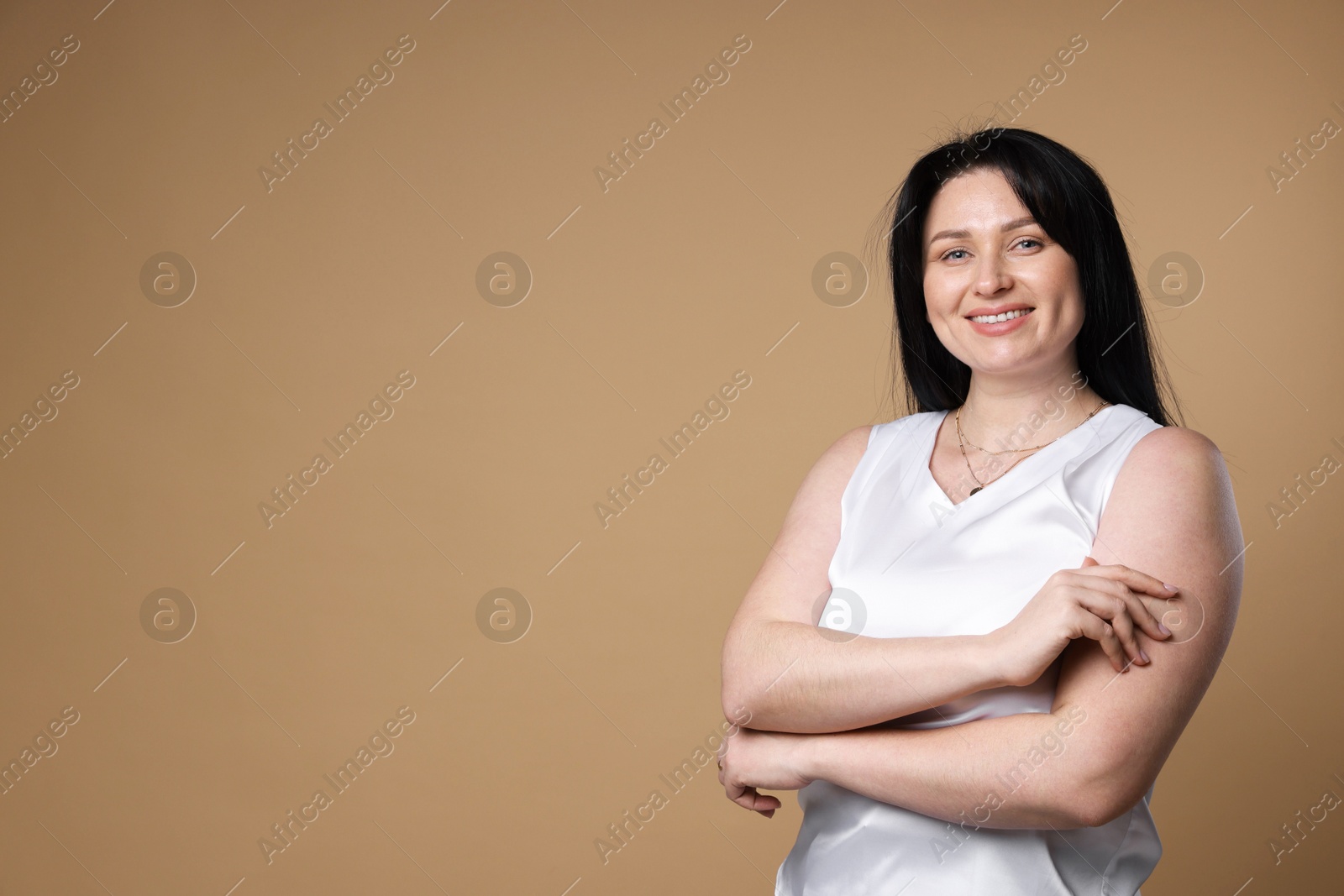 Photo of Portrait of smiling plus size model on beige background, space for text. Overweight