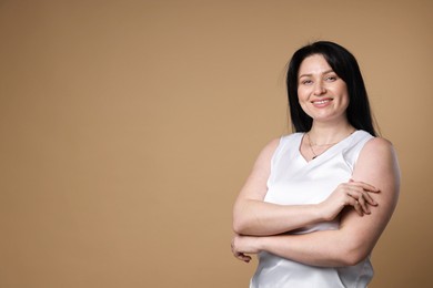 Portrait of smiling plus size model on beige background, space for text. Overweight